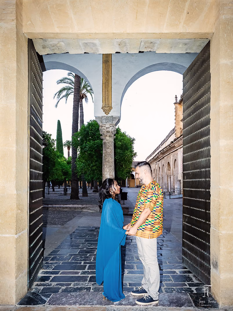 Pablo and Seraphine framed in a tall studded doorway of the Mezquita, the courtyard of orange trees beyond them.