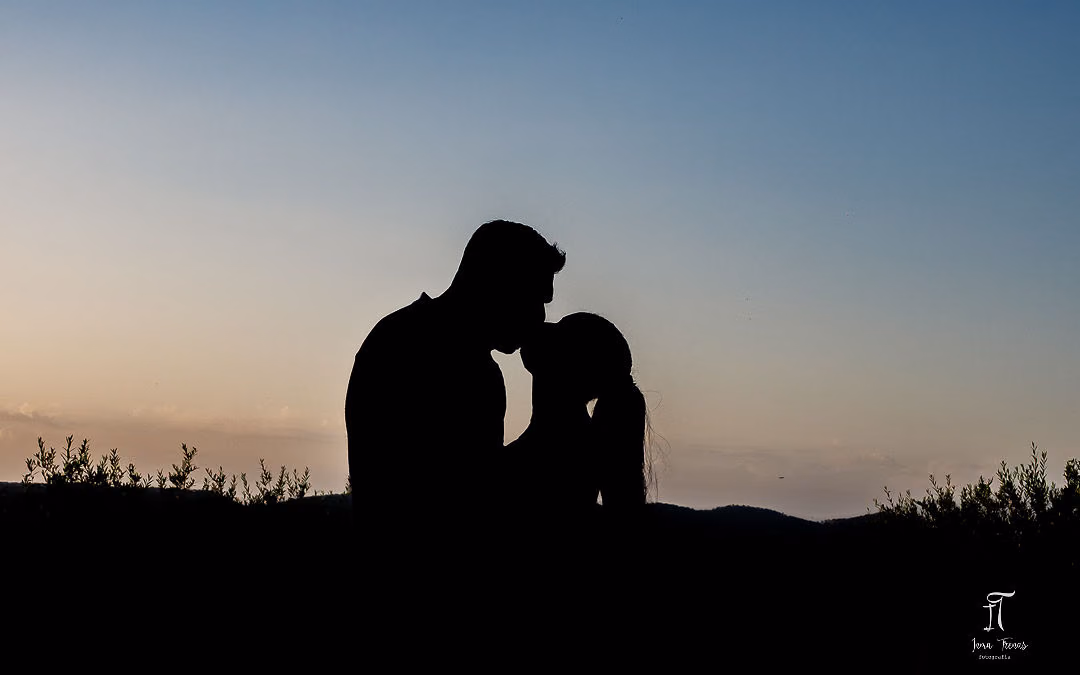 Pablo and Seraphine in silhouette against a dusk sky, foreheads almost touching.